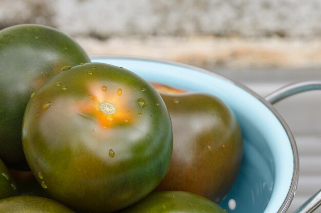 Nahaufnahme von unreifen Tomaten in einer Kolander auf dem Tisch