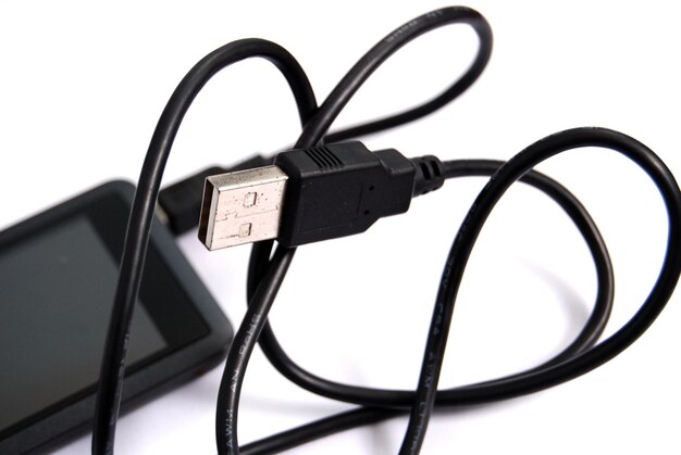 Nahaufnahme von USB-Kabel und Mobiltelefon auf weißem Hintergrund