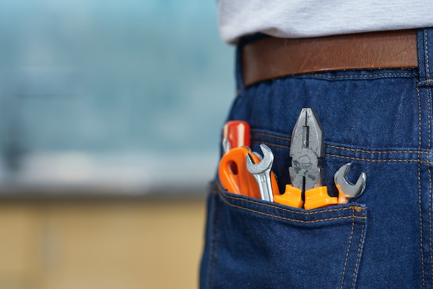 Nahaufnahme von verschiedenen Sanitärhandwerkzeugen in der Gesäßtasche der Jeans des Mannes