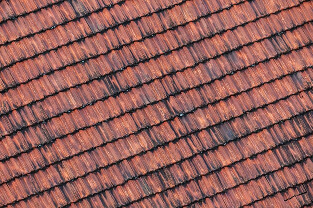 Nahaufnahme von verwitterten rostigen roten Fliesen auf dem Dach eines mittelalterlichen Gebäudes für einen strukturierten Hintergrund