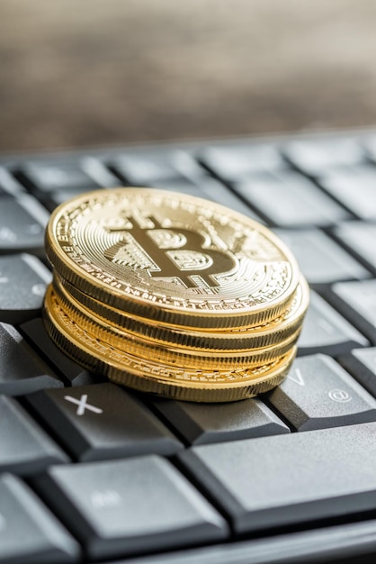 Nahaufnahme von vier goldenen Bitcoins auf einer Tastatur