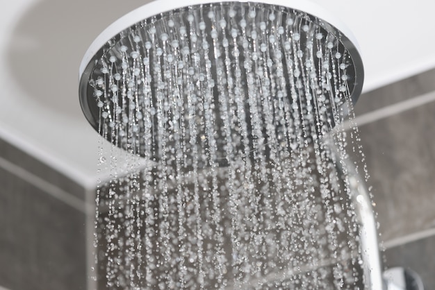 Nahaufnahme von Wasser fließt in kleinen Düsen von der Metallregen-Dusche im Badezimmer