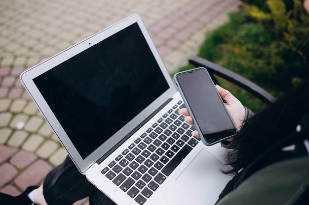 Nahaufnahme von weiblichen Händen, die Text auf einem Laptop mit leerem schwarzem Bildschirm mit Kopierbereich für Werbung auf dem städtischen Hintergrund eingeben Geschäftskonzept