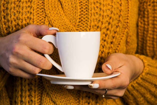 Nahaufnahme von weiblichen Händen mit einem Becher Getränk schöne Frau in schreien Pullover mit Tasse Tee