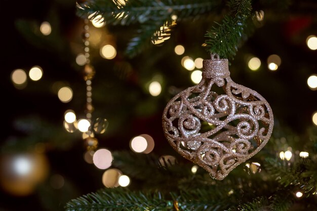 Nahaufnahme von Weihnachts-Festdekoration-Spielzeug, das an einem Tannenbaum-Zweig mit bokeh-blauen Lichtern hängt