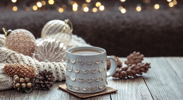 Nahaufnahme von Weihnachtsbecher und festlichem Dekor auf verschwommenem dunklem Hintergrund mit Bokeh.