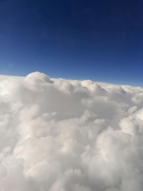 Nahaufnahme von Wolken aus einem Flugzeugfenster vor einem blauen Himmel