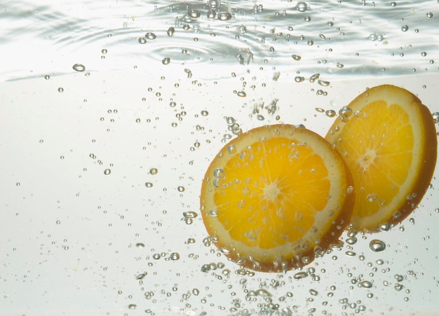 Nahaufnahme von Zitronenscheiben im Wasser vor weißem Hintergrund