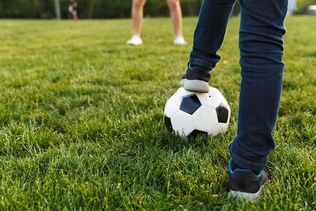 Nahaufnahme von zwei Brüdern, die Fußball auf dem Rasen im Park spielen