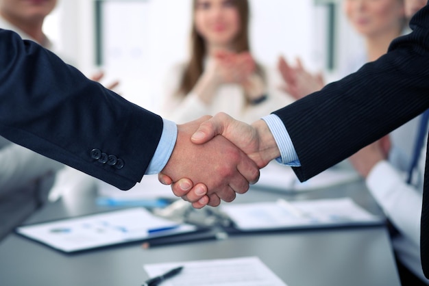Nahaufnahme von zwei Geschäftsleuten, die einander die Hand schütteln und das Treffen beenden.