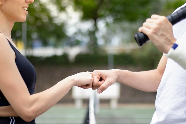 Nahaufnahme von zwei nicht erkennbaren Tennisspielern, die auf einem Tennisplatz aneinander stoßen