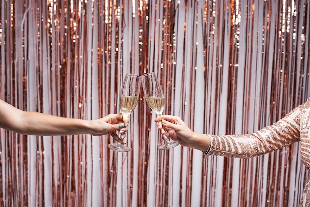 Nahaufnahme von zwei weiblichen Händen, die Champagnergläser klirren.
