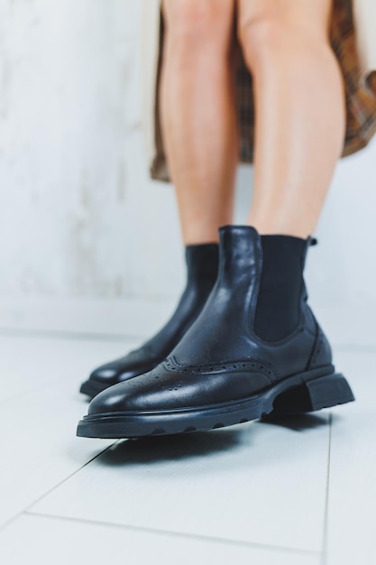 Nahaufnahme weiblicher Beine in Chelsea-Stiefeln aus schwarzem Leder Neue Herbstkollektion von Damenlederschuhen 2022