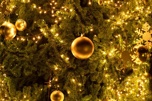 Nahaufnahme-weihnachtsbaum mit dekorations-, licht- und goldball nachts im weihnachts- und neujahrsfeiertag.