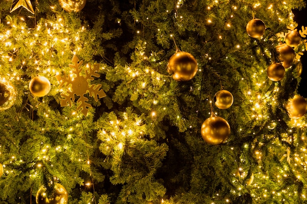 Nahaufnahme-Weihnachtsbaum mit Dekorations-, Licht- und Goldball nachts im Weihnachts- und Neujahrsfeiertag.