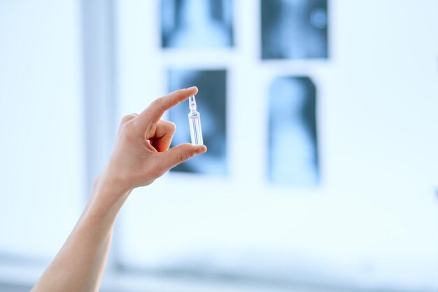 Nahaufnahmeampulle mit einem Impfstoff in der Hand eines glücklichen Wissenschaftlers