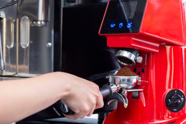 Nahaufnahmeaufnahme des professionellen Barkeepers, der Espressokaffee in der exklusiven Café-Bar oder in der Cafeteria zubereitet. Er benutzt eine Kaffeemühle oder eine Mühle.