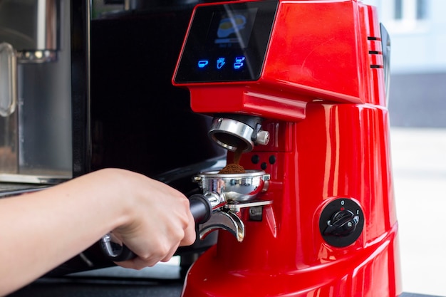 Nahaufnahmeaufnahme des professionellen Barkeepers, der Espressokaffee in der exklusiven Café-Bar oder in der Cafeteria zubereitet. Er benutzt eine Kaffeemühle oder eine Mühle.