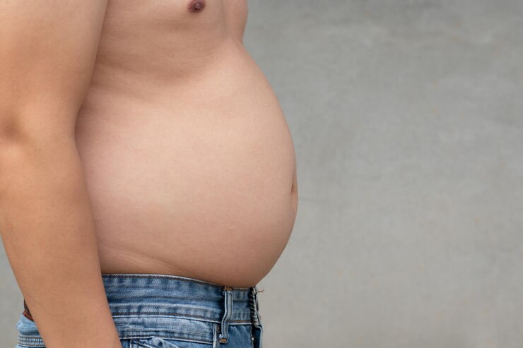 Nahaufnahmeaufnahme eines asiatischen Mannes mit übergewichtigem Magen mit Jeanshose und Zement verwischen Hintergrundplanungsübungen und Gewichtsabnahme für eine gute Gesundheit im Feature-Gesundheits- und Fitnesskonzept-Kopienraum