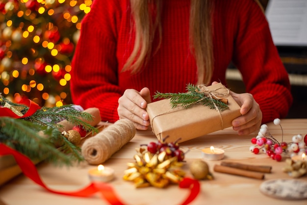 Nahaufnahmeaufnahme eines Mädchens, das Geschenke in Papier einwickelt und sie mit Zimttannenzweigen verziert