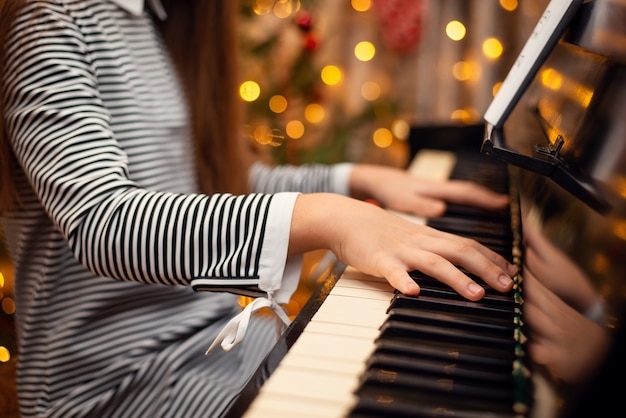 Nahaufnahmeaufnahme von Mädchenhänden auf Tastatur eines Klaviers