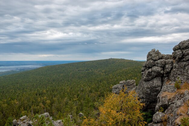 Nahaufnahmebergszenen im Nationalpark Kachkanar, Russland, Europa. Bewölktes Wetter, dramatischer blauer Himmel, weit entfernte grüne Bäume. Bunter Sommertag