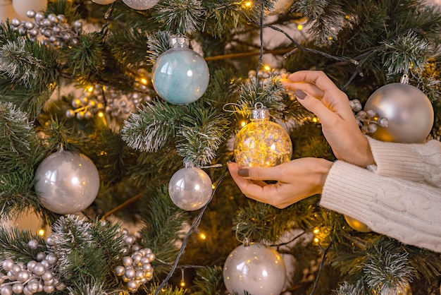 Nahaufnahmebild der Frau in der Strickjacke Weihnachtsbaum mit Flitter verzierend
