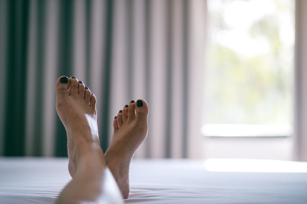 Nahaufnahmebild der Füße einer Frau auf einem weißen Bett