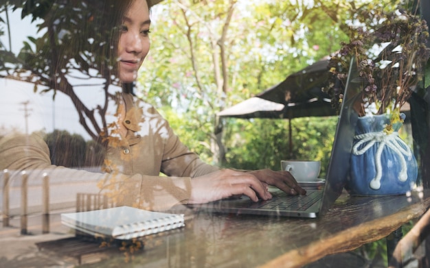 Nahaufnahmebild der Geschäftsfrau arbeitend und auf Laptoptastatur auf Holztisch schreibend