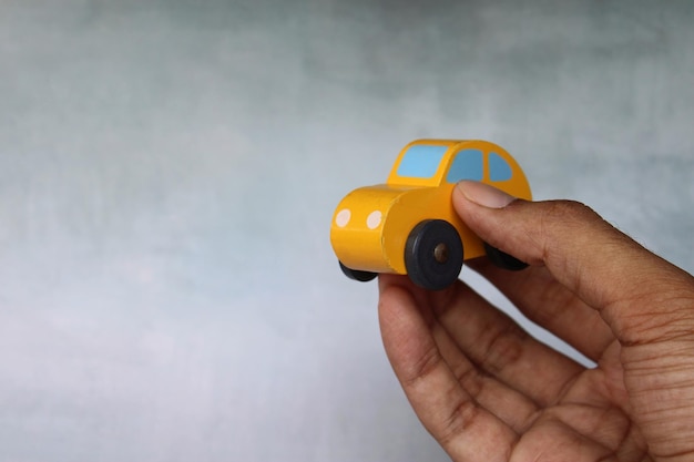 Nahaufnahmebild der Hand, die Spielzeugauto mit Kopienraum hält Transportkonzept