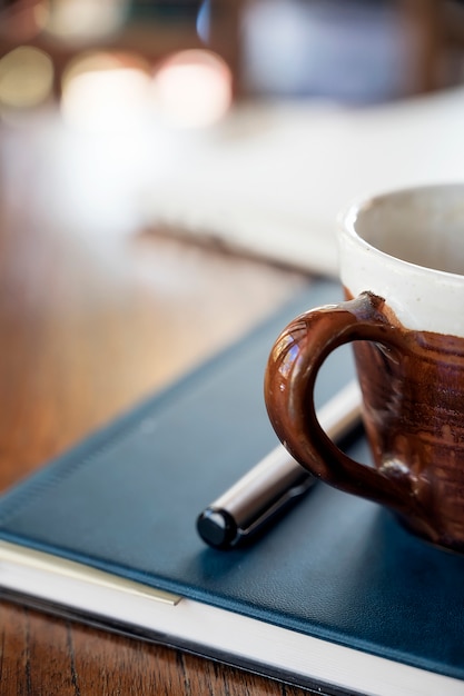 Nahaufnahmebild des Tasse Kaffees auf dem Buch mit Kopienraum.