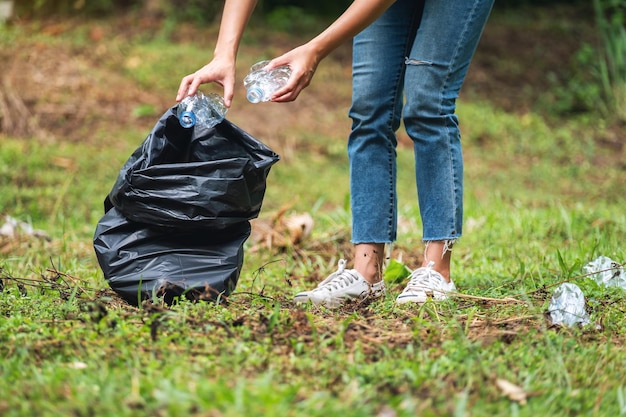 Nahaufnahmebild einer Aktivistin, die Müllplastikflaschen in einer Plastiktüte im Park für das Recyclingkonzept aufsammelt