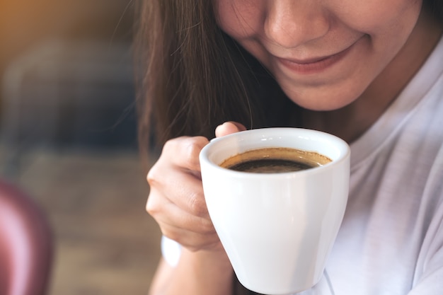 Nahaufnahmebild einer Asiatin, die eine Kaffeetasse vor dem Trinken hält