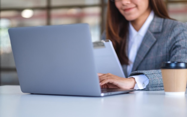 Nahaufnahmebild einer asiatischen Geschäftsfrau, die Laptop-Computer beim Arbeiten im Büro verwendet