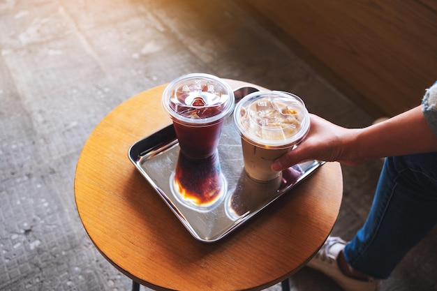 Nahaufnahmebild einer Frau, die einen Eiskaffee in einem rostfreien Tablett schnappt