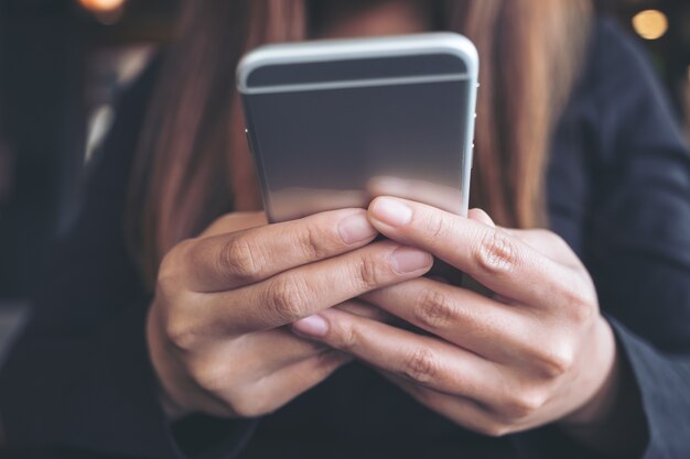 Nahaufnahmebild einer Frau, die intelligentes Telefon hält, verwendet und betrachtet