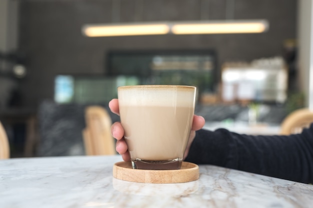 Nahaufnahmebild einer Frau, die Kaffeeglas im Café hält
