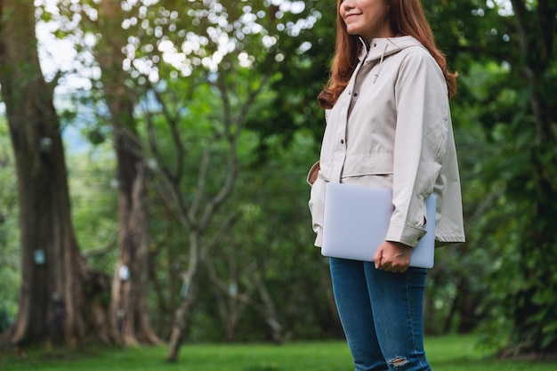 Nahaufnahmebild einer Frau, die Laptop-Computer im Park hält