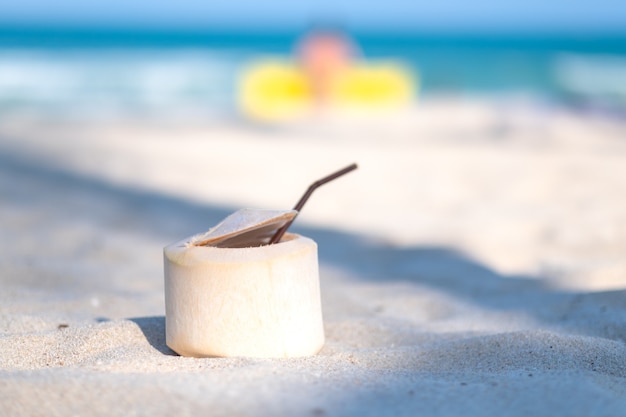 Nahaufnahmebild einer frischen Kokosnuss am Strand mit blauem Meerhintergrund