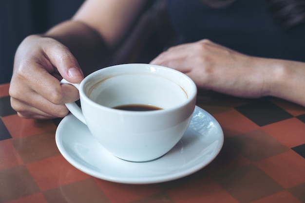 Nahaufnahmebild einer Hand, die heißen Kaffee im Café hält und trinkt