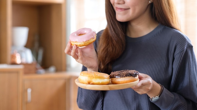 Nahaufnahmebild einer jungen Frau, die Donuts zu Hause hält und genoss, sie zu essen