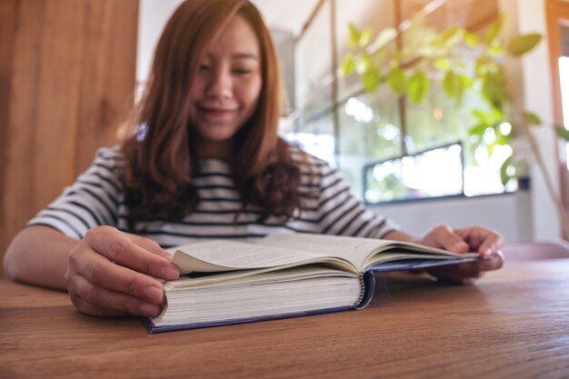 Nahaufnahmebild einer schönen asiatischen Frau, die ein Buch hält und liest