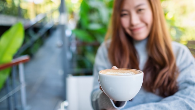 Nahaufnahmebild einer schönen asiatischen frau, die eine tasse heißen kaffees hält