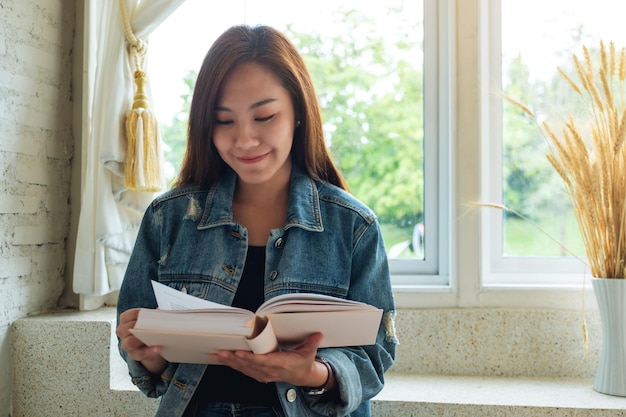 Nahaufnahmebild einer schönen asiatischen frau, die zu hause buch sitzt und liest