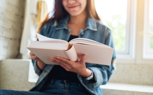 Nahaufnahmebild einer schönen asiatischen frau, die zu hause buch sitzt und liest