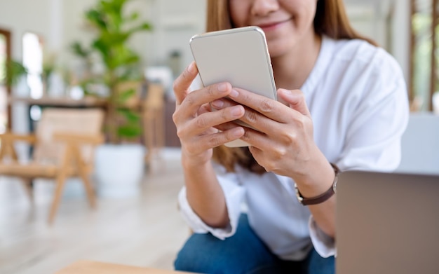 Nahaufnahmebild einer schönen jungen asiatischen Frau, die Handy hält und benutzt