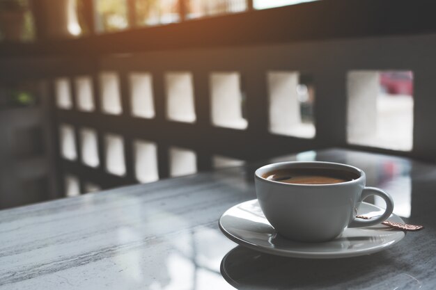 Nahaufnahmebild einer weißen Tasse heißen Kaffees auf Tisch im Café
