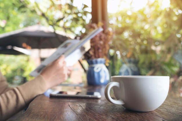 Nahaufnahmebild eines Frauenlesebuches und des trinkenden Kaffees im Café