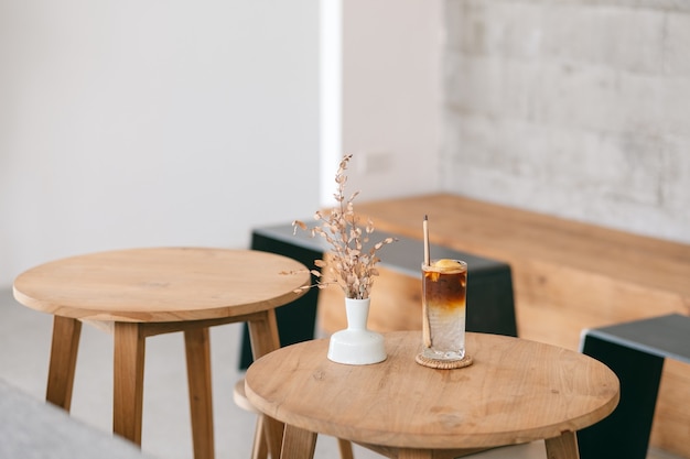 Nahaufnahmebild eines Glases Kokosnuss-Eiskaffee auf Holztisch in minimalem Café