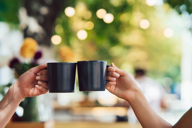 Nahaufnahmebild von Leuten, die zusammen Kaffeetassen im Café klirren